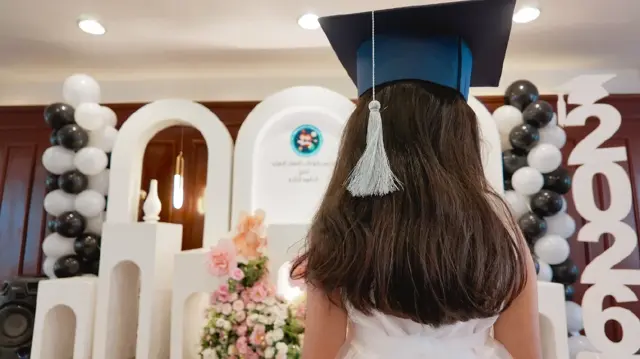 طفلة من الخلف ترتدي قبعة تخرج أمام تنسيق فعالية.