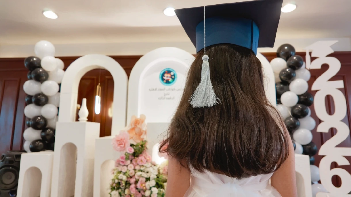 طفلة من الخلف ترتدي قبعة تخرج أمام تنسيق فعالية.