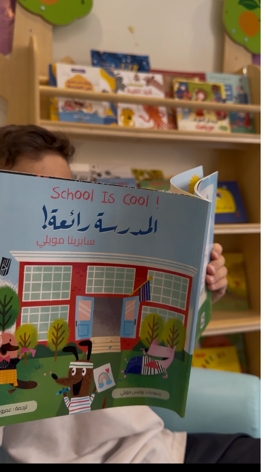 طفل يمسك كتابًا تعليميًا داخل بيئة مدرسية.